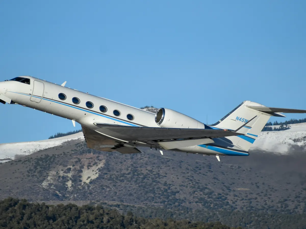 Business jet flying over snow-covered mountains