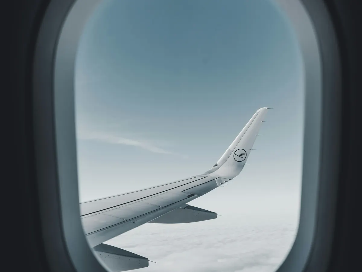 Wing and engine seen through an aircraft window above the clouds